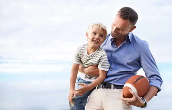 Blue sky, football and father with young son on outdoor adventure, playful or excited mockup space. Relax, bonding together and family, happy child and dad on summer holiday for fun, game and smile
