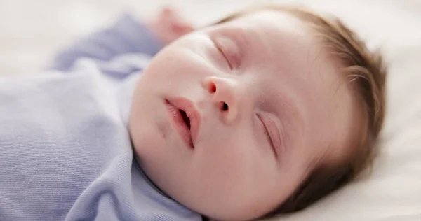 Face, relax and sleep with a baby on a bed closeup in a home, dreaming during a nap for child development. Growth, calm and rest with an adorable newborn infant asleep in a bedroom for comfort.