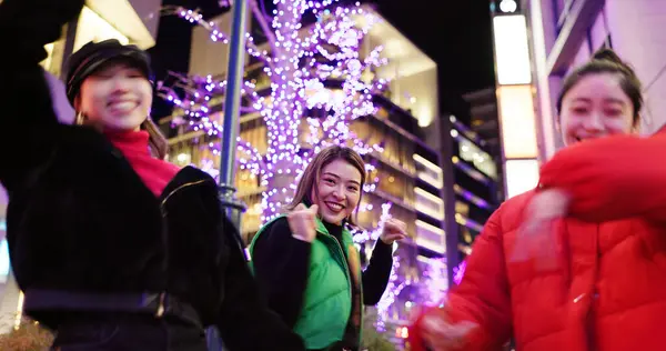 Japanese women at night, dancing in city and fun with energy, happiness and celebration outdoor. Freedom, dancer group and smile on urban street in Tokyo, friends together and gen z with nightlife.