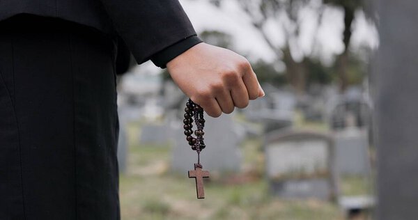 Rosary, death or hand cemetery for funeral. spiritual service or grave visit to repsect the Christian religion. Mourning, goodbye or closeup of person outside in graveyard for grief, loss or farewell.