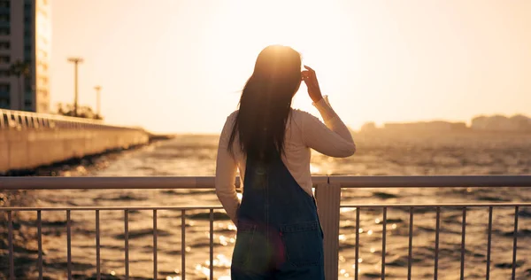 Back, woman and sea with sunset and view of horizon outdoor, travel and tourism with peace, calm and nature. Environment, ocean and traveller on adventure or journey, sunshine and wind in Kyoto.