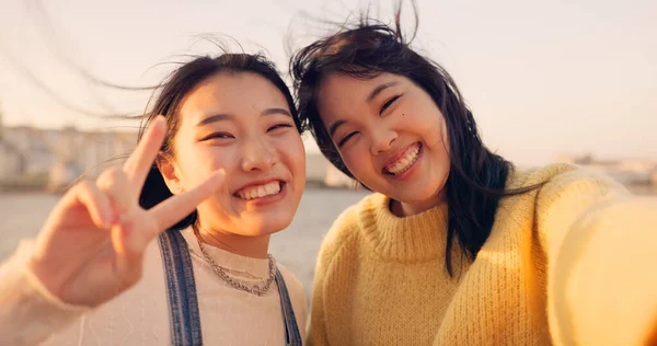 Women, friends and selfie at sea holiday in Japan for travel experience, adventure or happy. Female people, peace sign and face for city tour trip or online connection for summer, social or vacation.