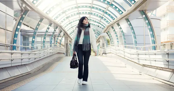 Bridge, thinking and Japanese woman in city on commute, travel and journey in metro. Walking, fashion and person with trendy clothes, casual style and bag for adventure, holiday and vacation in town.
