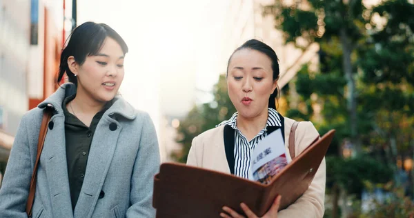 Talking, walking and Japanese women with a document in the city for business or teamwork on a project. Morning, smile and hr manager in Japan reading a report with an employee for recruitment.