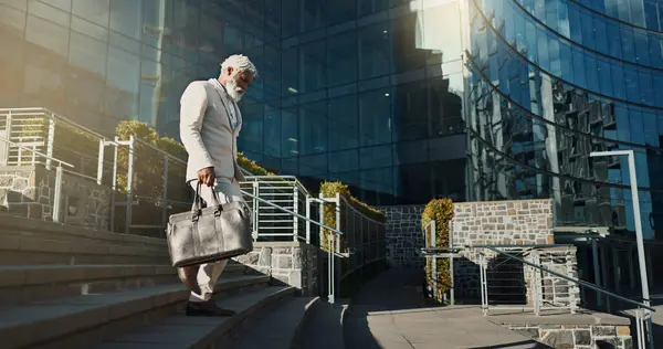 City, business and stairs with old man, walking and corporate with a briefcase, sunshine and buildings. Elderly person, employee and entrepreneur with urban town, steps and New York with professional.