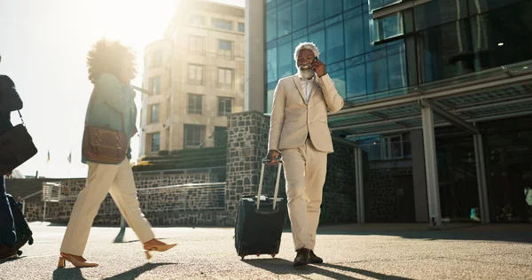 Business man, phone call and suitcase in city, street or conversation for booking, travel or transportation. Senior corporate executive, smartphone or luggage on talk, chat or sidewalk in Cape Town.
