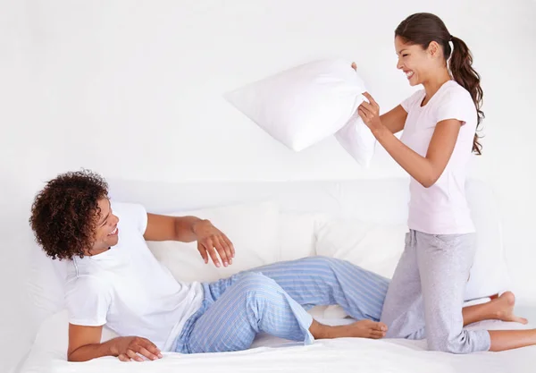 Man, woman and pillow fight for funny game on morning holiday for love connection, game or vacation. Happy partnership, cushion and pajamas or laughing in home for play couple comedy, joy or smile.