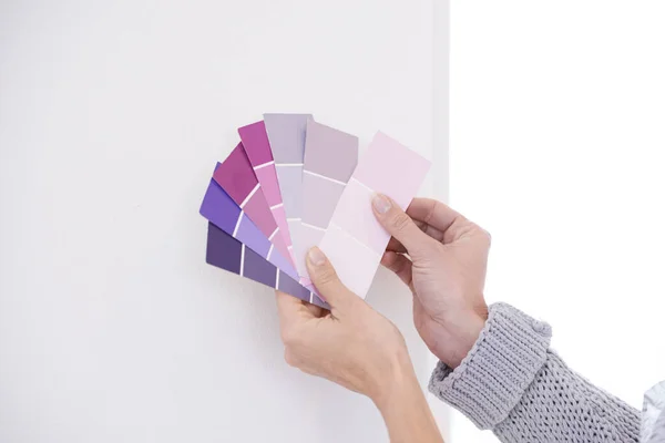 Hands, color swatches for interior design and paint choice, home renovation and person for development and plan. DIY project, painter decision and palette for creativity and decor on wall background.