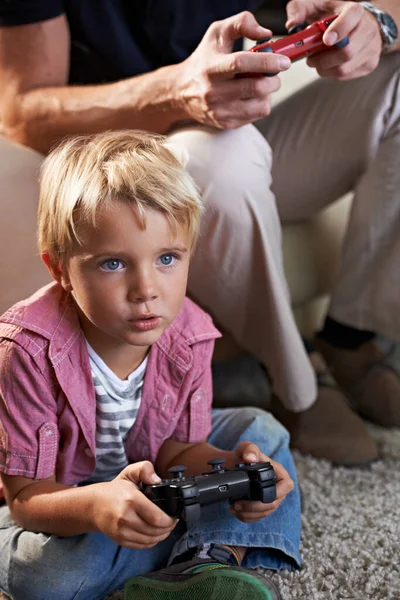 Family, serious and boy child gaming on floor in living room of home with father for love, competition or child development. Video game, controller for next level and son gamer playing with dad.
