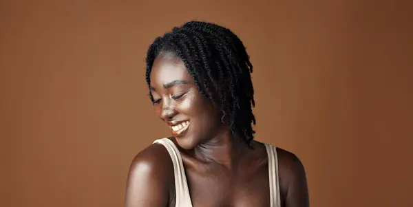 Face, beauty and aesthetic with funny black woman in studio isolated on brown background for wellness. Portrait, skincare and laughing for natural cosmetics or foundation with confident young person.
