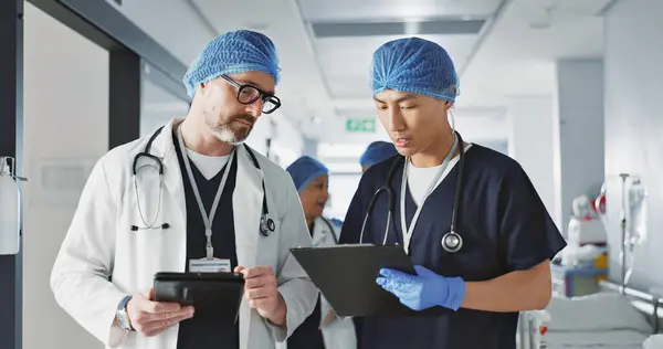 Teamwork, talking and doctors with a tablet at a hospital for health advice or surgery communication. Help, clinic and medical employees speaking with technology, planning and schedule for nursing.