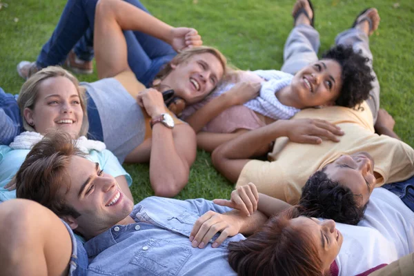 Relax, friends and happy group on grass at park on vacation, holiday or summer. People, smile and team of students on lawn at garden, circle in nature or freedom of young community together outdoor.