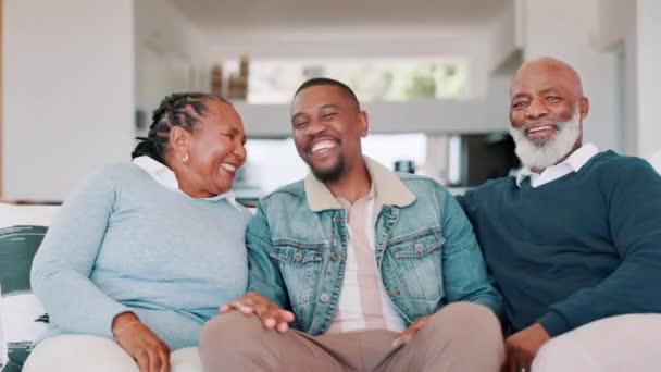 年事已高的父母 在沙发上笑着度假 在客厅里开心地开玩笑 谈情说爱或放松 黑人家庭 老夫老妻以及与即将退休的儿子的关系 探访或爱情 — 图库视频影像