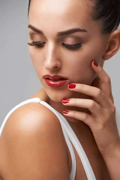 Makeup, woman for beauty and manicure in studio, nail polish and lashes with skin and cosmetics on grey background. Red lipstick, color nails and glamour with mascara for confidence and elegance.
