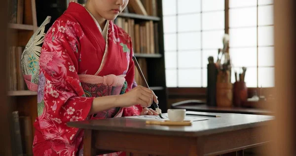 Ink, writing and hands of Japanese woman for traditional script on paper, documents and page. Creative, Asian culture and person with vintage paintbrush tools for calligraphy, font and text in home.