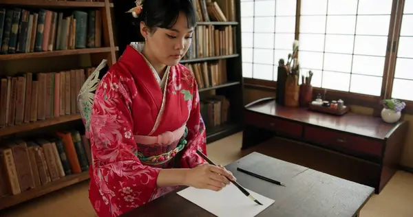 Ink, writing and Japanese woman in home for traditional script on paper, documents and page. Creative, Asian culture and person with vintage paintbrush tools for calligraphy, font and text in house.