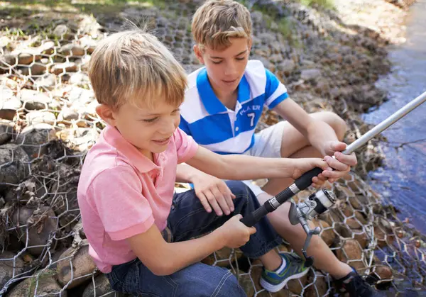 Children, friends and fishing rod at river for summer holiday at countryside for vacation, learning or travel. Kids, boys and happy for catch adventure at lake for bonding teamwork, teaching or relax.
