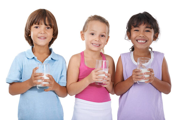Milk, glasses and happy portrait of children with nutrition, health and wellness in white background of studio. Calcium, drink and kids smile with dairy, protein and benefits in diet for growth.