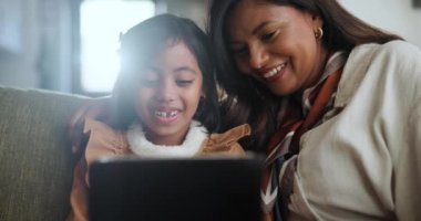 Evde, tabletli anne ve kız, gülümseme ve internet oyunlarıyla ve sosyal medyayla bağlantı. Daire, aile ya da kızı olan anne ya da çocuk gelişimi olan teknoloji ya da çizgi film izlemek.