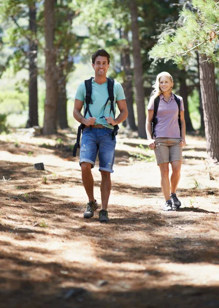 Couple of friends, travel and hiking in forest for fitness, outdoor adventure and wellness or health in nature. Portrait of happy man and woman walking and trekking with backpack on path and journey.
