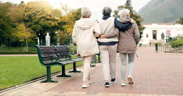 Senior friends, talking and walking together on an outdoor path to relax in nature with elderly women in retirement. Happy, people pointing and conversation in the park or woods in autumn or winter.