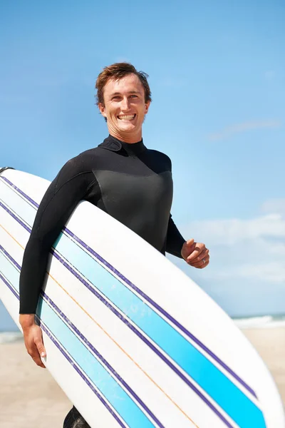 Beach, smile and man with surfboard for exercise, fitness workout or body health in summer outdoor. Surfer, wetsuit and happy person by ocean for water sports, travel or holiday vacation in Hawaii.