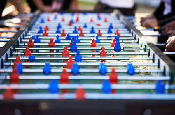 Foosball table, competitive and leisure with people playing a game outdoor at a music festival together. Party, event or social gathering with friends at a carnival for tabletop soccer or football.