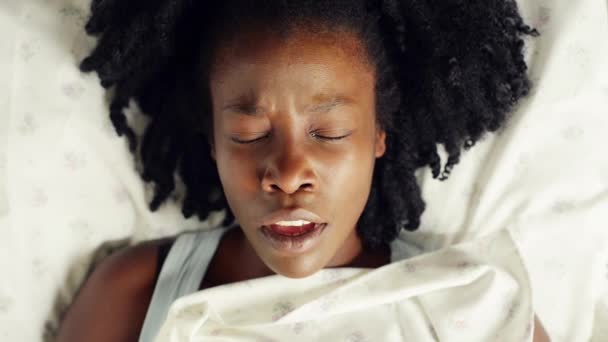 女性は 上から目を覚まし 朝から不眠症 週末または怠惰のためにリラックスするために ベッドで顔とヨーン 疲れた睡眠または過労 健康または燃え尽きのためのリネン羽毛布団で黒人 アフロと疲れています — ストック動画