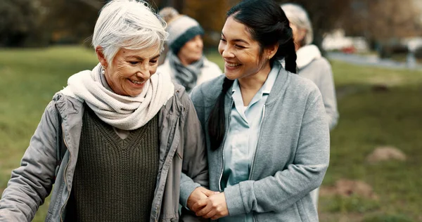 Happy, walking and a woman and caregiver in nature for talking, support and relax in the morning. Help, together and a young carer speaking to a senior patient in a park or garden for bonding.