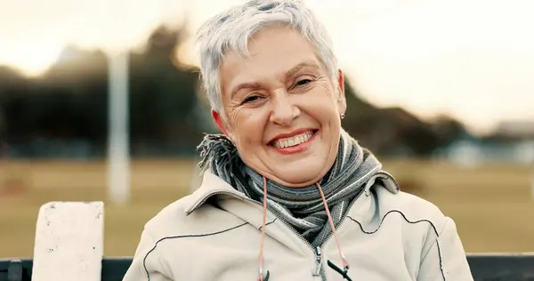 Face, senior woman and funny on park bench on vacation, holiday or travel in winter. Portrait, happy and elderly person in nature, outdoor or garden for laughing, freedom and retirement in Australia.