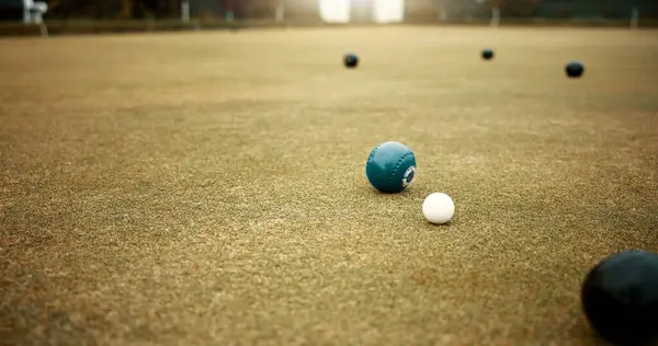 Green, balls and game of lawn bowling on grass, field or pitch in match or competition of outdoor bowls. Ball, moving and sport tournament at bowlers club, league or championship games on the ground.