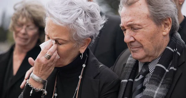 Death, funeral and senior couple crying together in pain or grief for loss during a ceremony or memorial service. Tissue for tears, support or empathy with an elderly man and woman feeling compassion.