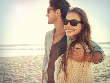 Çift, deniz ve güneş gözlüklü, sarılan, gülümseyen ya da moda, göz koruması ya da yaz tatili seven. Erkek, kadın ve plajda güneş gözlükleriyle kucaklaşmak, tropikal tatilde okyanus kenarında mutlu ve sevgi.