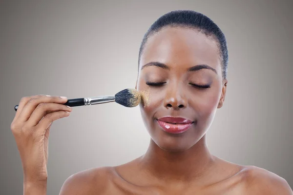 美しさとメイクブラシ グレーの背景にスタジオで若い黒人女性と頬にブラシを適用する メイクオーバーのための高級化粧品を使用した自信を持ったモデルによる審美的 製品と基盤 — ストック写真