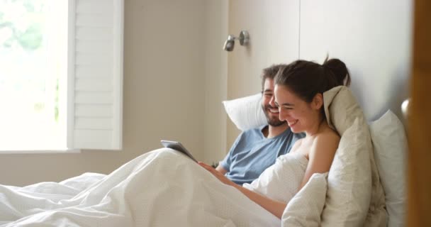 放松和快乐的夫妇在床上与平板社交媒体 视频或流媒体电影在他们的家 使用电子图书应用程序 订阅或注册服务选择的数字 搜索和卧房人员 — 图库视频影像