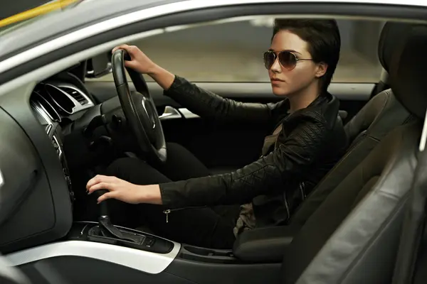 Woman, car and cool style while driving for a roadtrip adventure in a luxury vehicle. Female person, sunglasses and steering wheel of a transportation motor for trip with ride to travel destination.