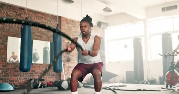 フィットネス バトルロープ またはレジリエンスまたはパワーでトレーニングのためのジムでの黒人男性トレーニング 筋肉や発達のための運動中のハードワーク エネルギーまたは健康なアフリカのスポーツ選手 — ストック動画