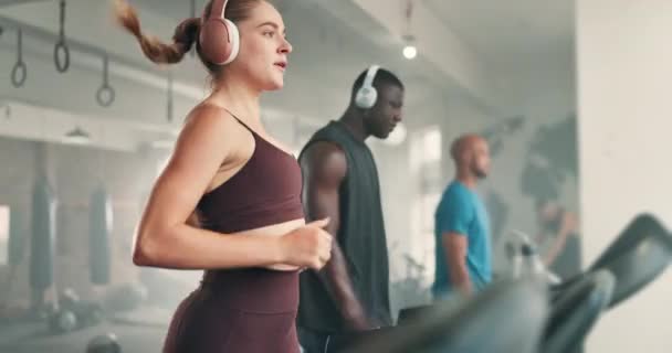 身体健康 在跑步机上跑步 带耳机进行有氧运动 锻炼或在健身房训练 女运动员在健身俱乐部运动的固定式机器上的女运动员或女运动员组 — 图库视频影像
