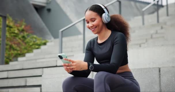 智能手机和快乐的女人在户外耳机上 在城市里打字或一步一步地流淌着收音机的声音 体育和在社交媒体上听手机应用程序 音频或滚动音乐的人 — 图库视频影像