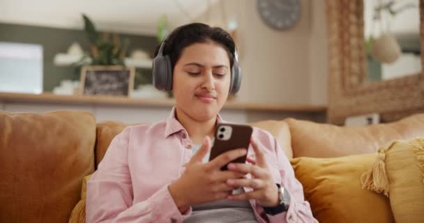 周末或休息时 耳机和手机在沙发上听音乐或流行歌曲 年轻人在智能手机和电子产品 听音频为网站订阅服务 — 图库视频影像