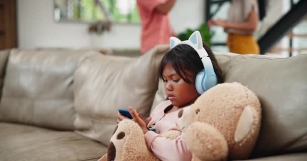 与父母在客厅沙发上争论 争执或离婚的孩子 电话和耳机 在家庭冲突中与泰迪熊一起玩手机的小女孩或女儿 — 图库视频影像