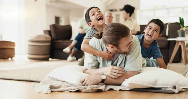 Funny, playing and father with children on floor in home living room laughing at comedy, joke or humor. Happy, dad and kids having fun, bonding and enjoying family time together in adoption house