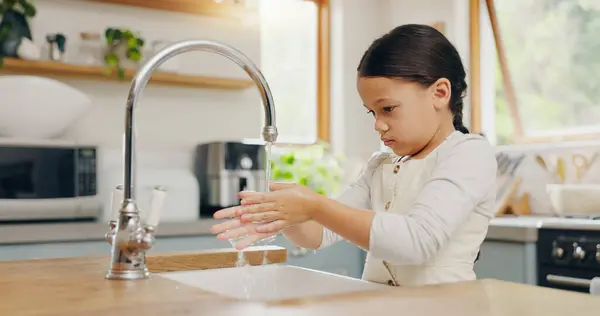 Water, washing hands and girl child in kitchen for hygiene, safety and responsibility in her home. Splash, cleaning and female kid at a sink for palm scrub, learning and care, bacteria or prevention.