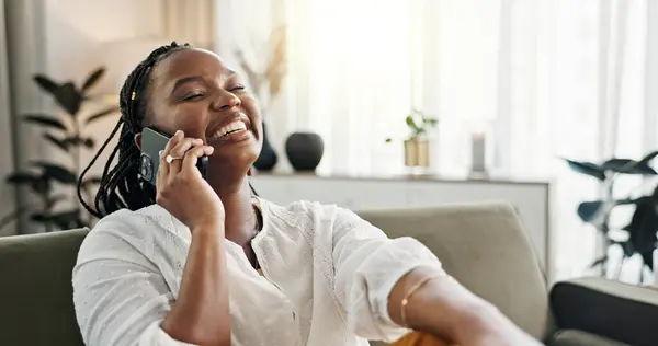 Funny, phone call and black woman on sofa, conversation or communication at home. Smartphone, talking and African person laughing, listening to story and comedy, chat or news and happy in living room.
