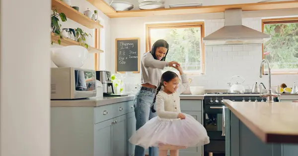 Dance, ballet and girl with mother in a kitchen together or mom support child and playing as a dancer or ballerina. Tutu skirt, mommy and woman dancing, bonding or spin with kid in house or home.