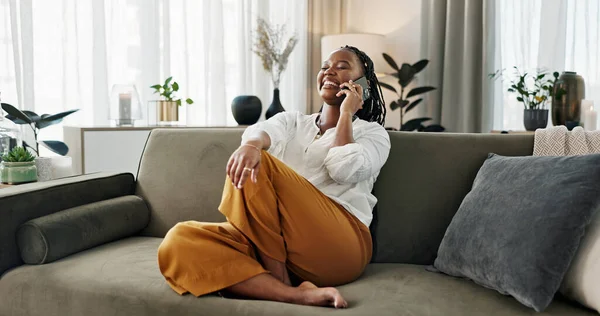 Funny, phone call and black woman in home, talking or communication on sofa. Smartphone, conversation and African person laughing, listening to story and comedy, chat or news and happy in living room.