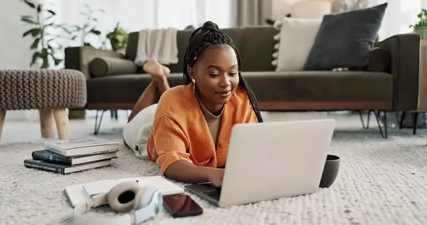 Laptop, education and a student black woman on the floor of a living room to study for a test or exam. Computer, smile and a happy young person learning with an online course for upskill development.