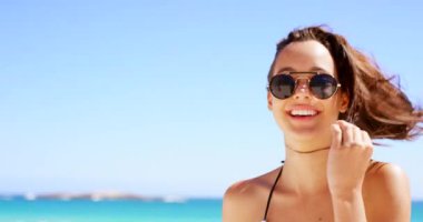 Plaj, seyahat ve güneş gözlüklü bir kadın ve yazın okyanusta rahatlamak için tarzıyla mutlu. Kız, gülümse ve mavi gökyüzü, deniz ve açık havada tatilde ya da tatilde macera yaşayan kişinin portresi.