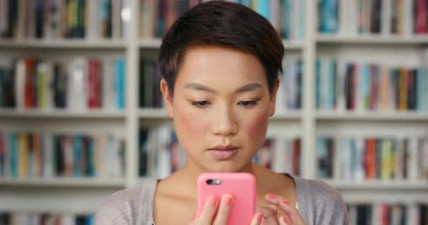 図書館 アジアの女性は 大学での学習 知識のためにオンラインで携帯電話を持っています 書店のインターネット ウェブサイト ソーシャルメディアのためのスマートフォン上の教育 大学および人 — ストック動画