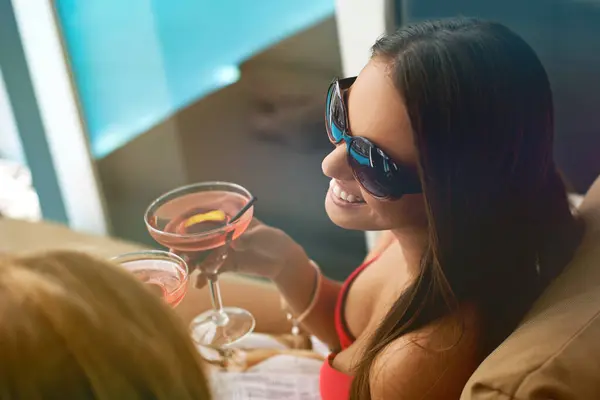 Women, friends and cocktail at swimming pool for summer party with alcohol for relax, sunshine or vacation. Female people, drinks and cheers on patio in Miami for bikini holiday, bonding or weekend.